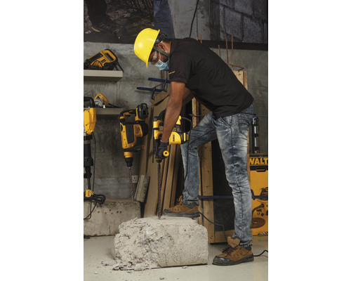 Robotník s ochrannou prilbou používa vŕtacie kladivo na opracovanie kusu betónu.