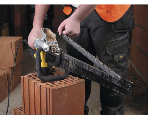 Muž montuje elektrickú reťazovú pílu na tehlu.