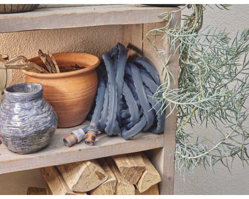 Záhradná hadica na drevenej polici s kvetináčmi a rastlinou