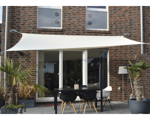 Scéna so slnečnou plachtou nad záhradným stolom pred domom