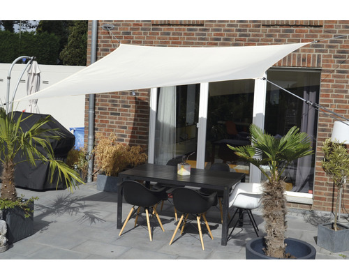 Terasa so slnečnou plachtou, záhradným stolom a stoličkami pred stenou domu