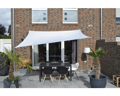 Terasa so slnečnou plachtou, stolom a stoličkami pred domom