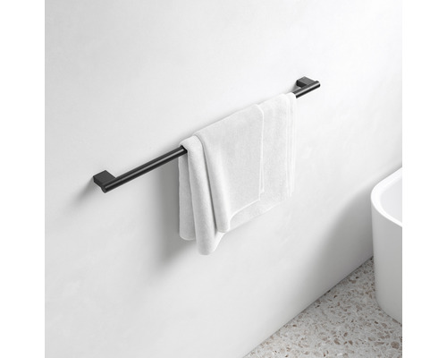 Čierny držiak na uteráky s uterákom na stene kúpeľne