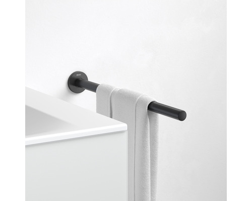 Čierny držiak na uteráky s uterákom namontovaný na bielej stene