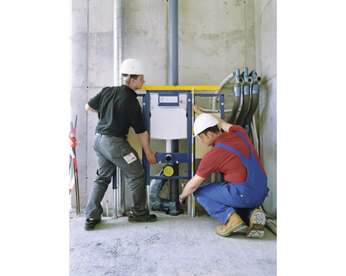 Dvaja remeselníci inštalujú predstenovú inštaláciu pre WC v hrubej stavbe.