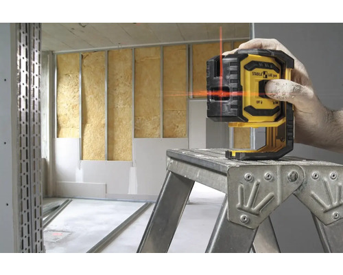 Logo spoločnosti Stabila. Osoba používa čiarový laser v miestnosti v stave hrubej stavby.