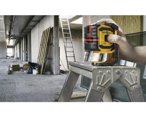 Čiarový laser Stabila na pracovnej plošine v hrubej stavbe.