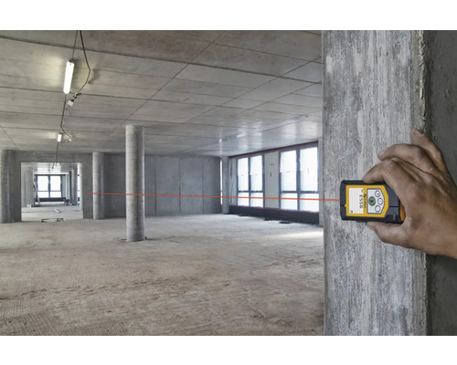 Miestnosť vo výstavbe s rukou ovládajúcou laserový diaľkomer