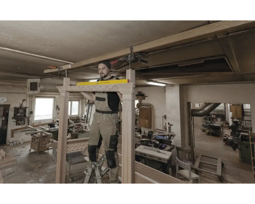 Remeselník montuje drevenú konštrukciu s vodováhou v dielni