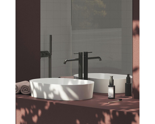 Moderná kúpeľňa s umývadlom na dosku, vodovodnou batériou, zrkadlom a uterákmi.