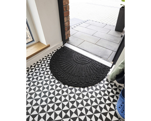 Polkruhová textilná rohožka pred vchodovými dverami na podlahe s geometrickým vzorom