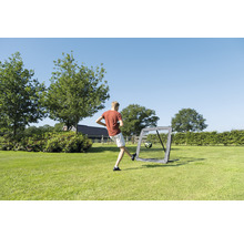 Chlapec kopne futbal do prenosnej futbalovej bránky v záhrade.