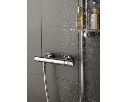 Nástenná sprchová batéria so sprchovou hadicou a fľašami šampónu v sprchovom kúte