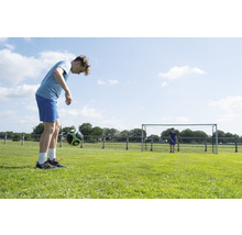 Mladík žongluje s futbalovou loptou na futbalovom ihrisku.