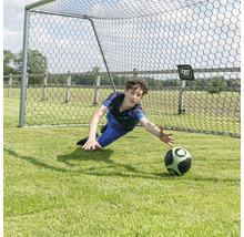 Chlapec drží futbalovú loptu pred futbalovou bránkou.