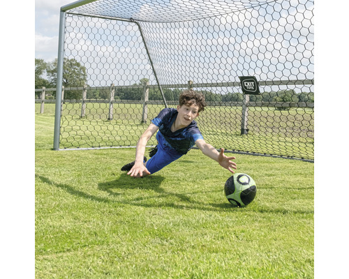 Chlapec drží futbalovú loptu pred futbalovou bránkou.
