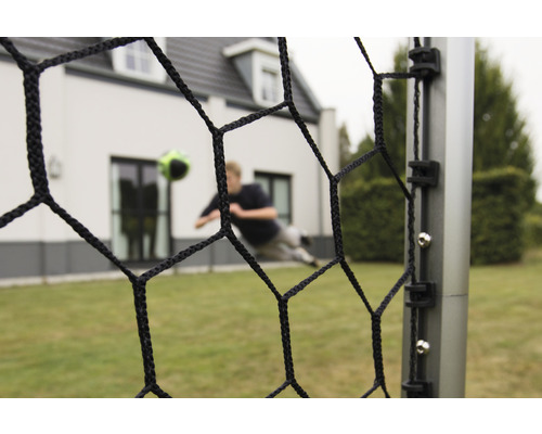 Futbalová bránka so sieťou a futbalistom v pozadí