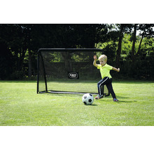 Chlapec hrá futbal pred futbalovou bránkou v záhrade.