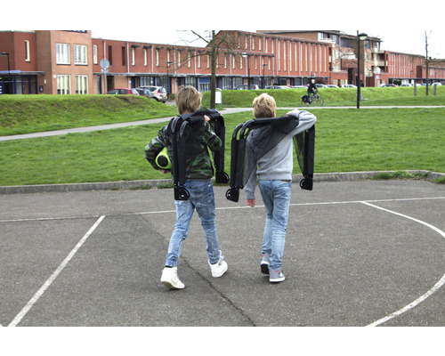 Dve deti nesú zložené vozíky na školskom dvore.