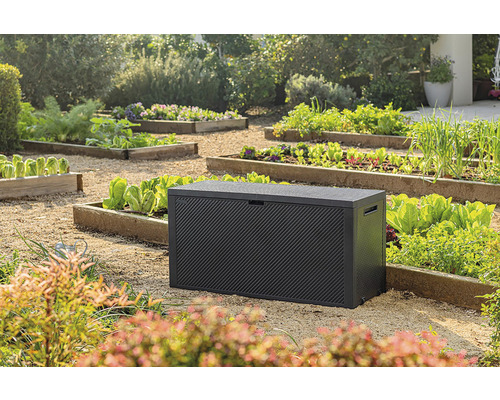Záhradná scéna s čiernym úložným boxom na vonkajšie použitie, obklopeným vyvýšenými záhonmi so zeleninou