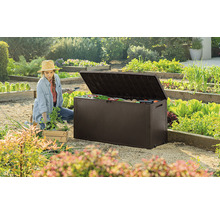 Záhradná scéna so ženou pracujúcou v blízkosti otvoreného hnedého záhradného boxu