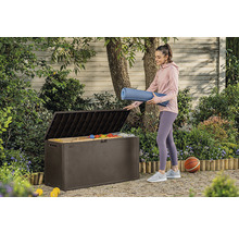 Žena ukladá podložku na jogu do hnedej záhradnej bedne vonku.