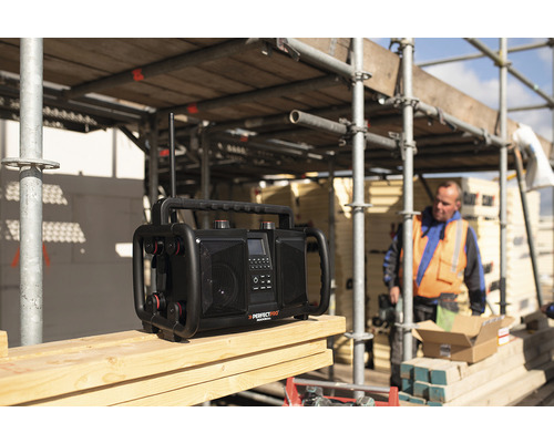 Stavebné rádio na drevenom povrchu so stavebným robotníkom v pozadí