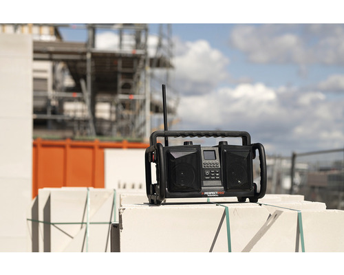 Stavebné rádio na murive so stavebným lešením v pozadí