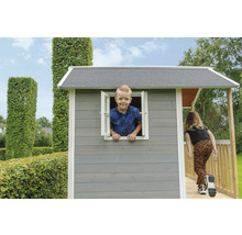 Dieťa sa hrá v sivom drevenom domčeku s rampou a oknom