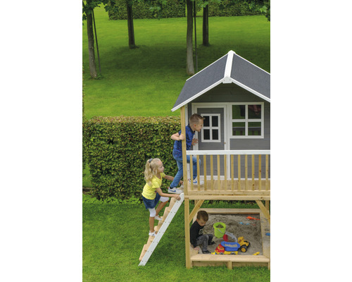 Detský domček s pieskoviskom a hrajúcimi sa deťmi v záhrade.