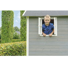 Chlapec sa pozerá z okna dreveného hracieho domčeka