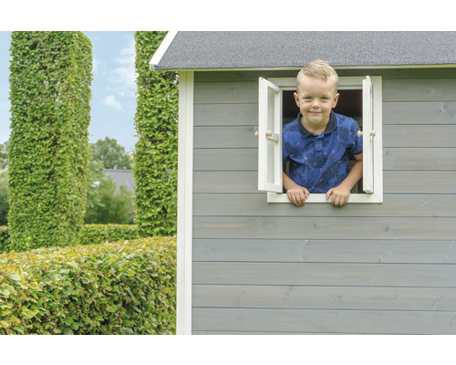 Chlapec sa pozerá z okna dreveného hracieho domčeka