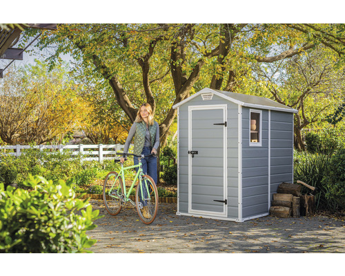 Záhradná scéna so záhradným domčekom, bicyklom a ženou v záhrade