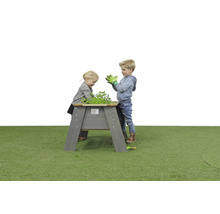 Deti sa hrajú s vyvýšeným dreveným záhonom v záhrade.