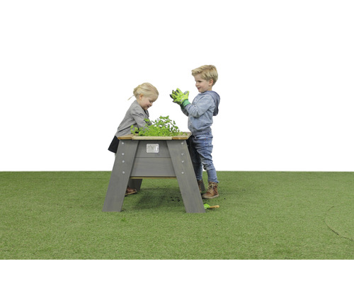 Deti sa hrajú s vyvýšeným dreveným záhonom v záhrade.