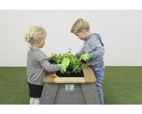 Deti sa hrajú s vyvýšeným záhonom v záhrade.