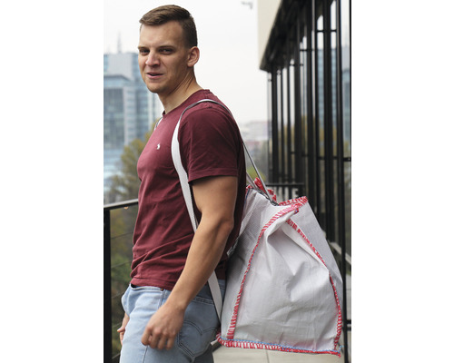 Muž s vakom stavebnej sute na ramene pred budovou