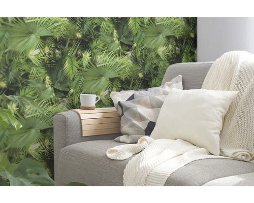 Sivá pohovka s vankúšmi, držiakom na nápoje a tropickou fototapetou