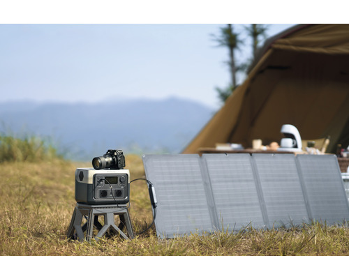 Vonkajšia fotografická scéna so solárnym panelom, generátorom prúdu a kamerou pred stanom