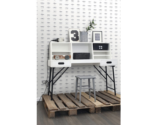 Scéna so stolom, stoličkou a dekoratívnymi prvkami pred stenou so vzorom uzlov.