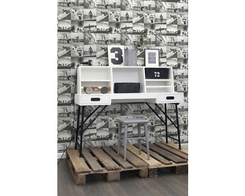 Písací stôl s policami, stolička a dekorácia na paletách pred fototapetou s plážovými motívmi.