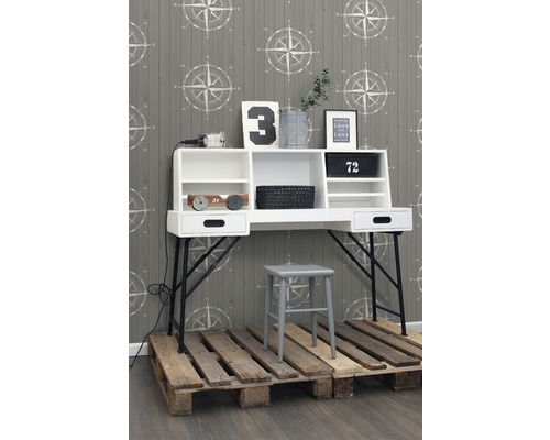 Pracovňa s bielym písacím stolom, sivou stoličkou a drevenou paletovou podlahou pred tapetou so vzorom kompasu