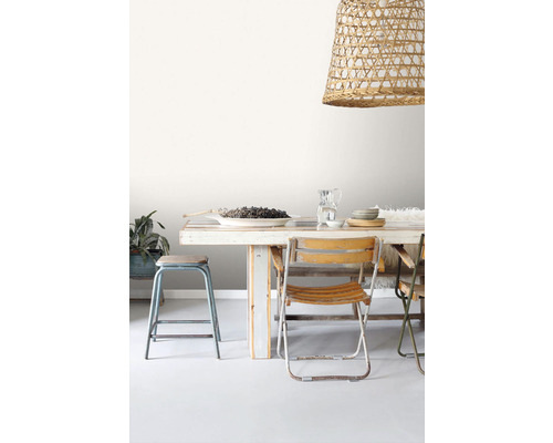 Jedálenský stôl so stoličkami a ozdobnou závesnou lampou z ratanu.