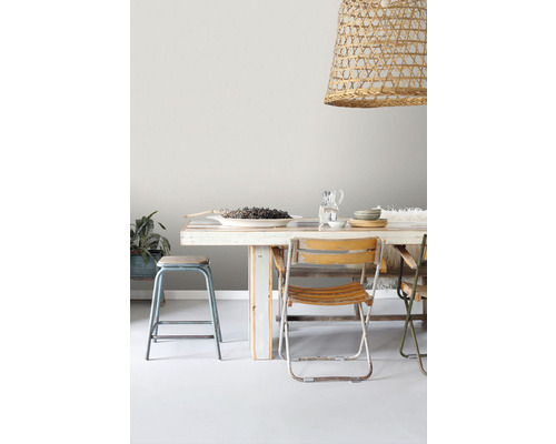 Jedálenský stôl so stoličkami a závesnou lampou z ratanu.