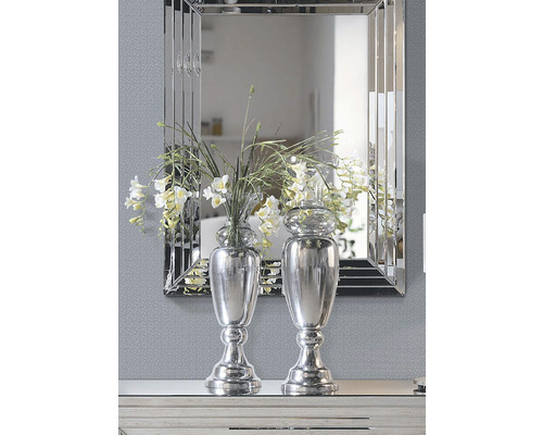 Dve strieborné vázy s kvetmi pred zrkadlom.