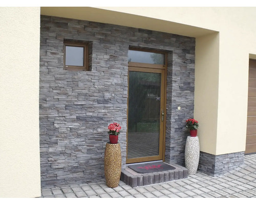 Exteriér domu s kamenným obkladom na fasáde a ozdobnými kvetináčmi.