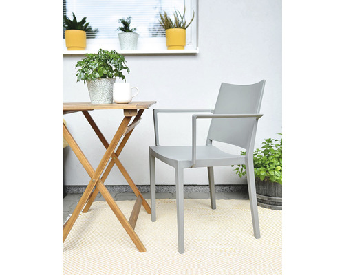 Scéna s dreveným stolom, sivým kreslom a izbovými rastlinami na balkóne