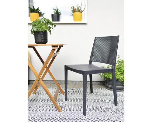 Záhradná scéna s dreveným stolom, plastovou stoličkou a rastlinami na koberci