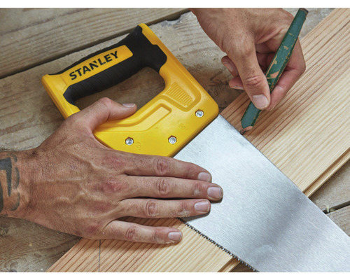 Ručná píla s kusom dreva a ceruzkou v ruke.