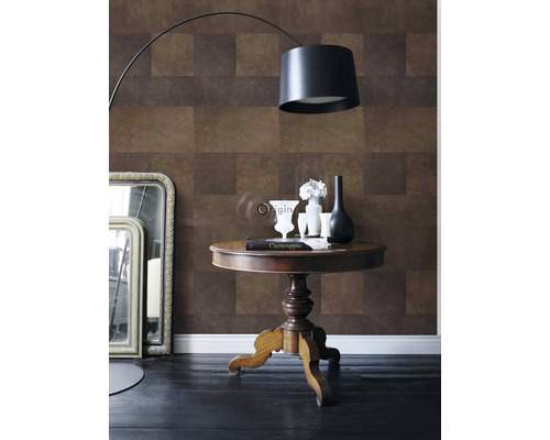 Pohľad do miestnosti s hnedou vzorovanou tapetou, stojacou lampou a dekoráciou na stole.